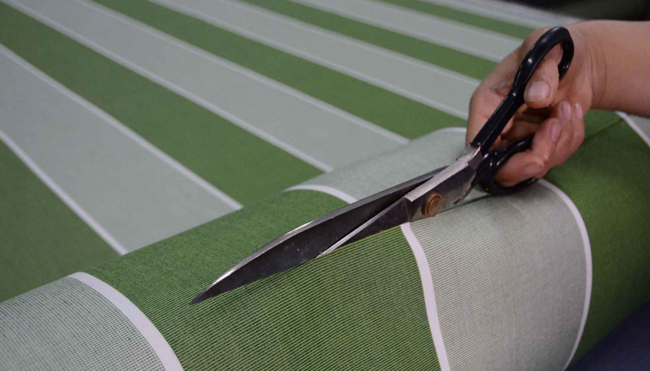 Green and grey striped outdoor fabric being cut